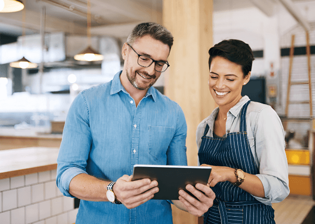 Customer success manager reviewing implementation progress with a hospitality manager using a tablet