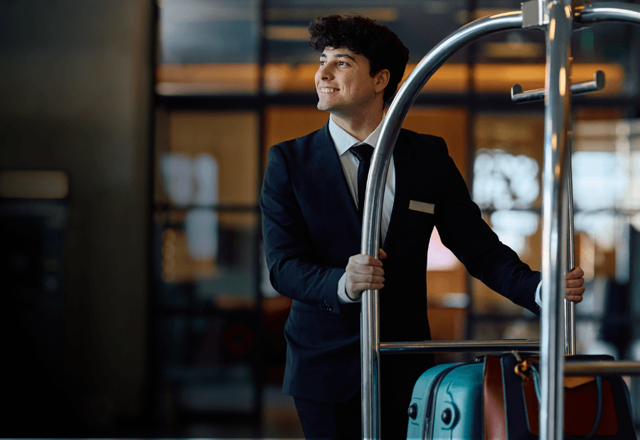 Hotel employee managing guest arrivals while hospitality leaders monitor workforce performance across multiple properties