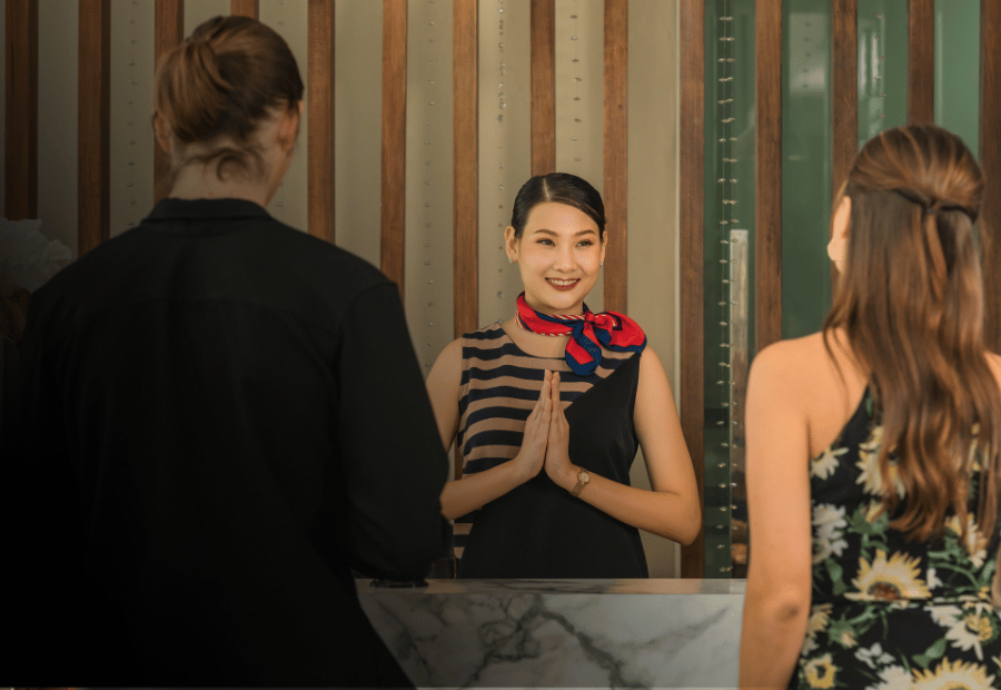 Hotel receptionist assisting two guests at the front desk.