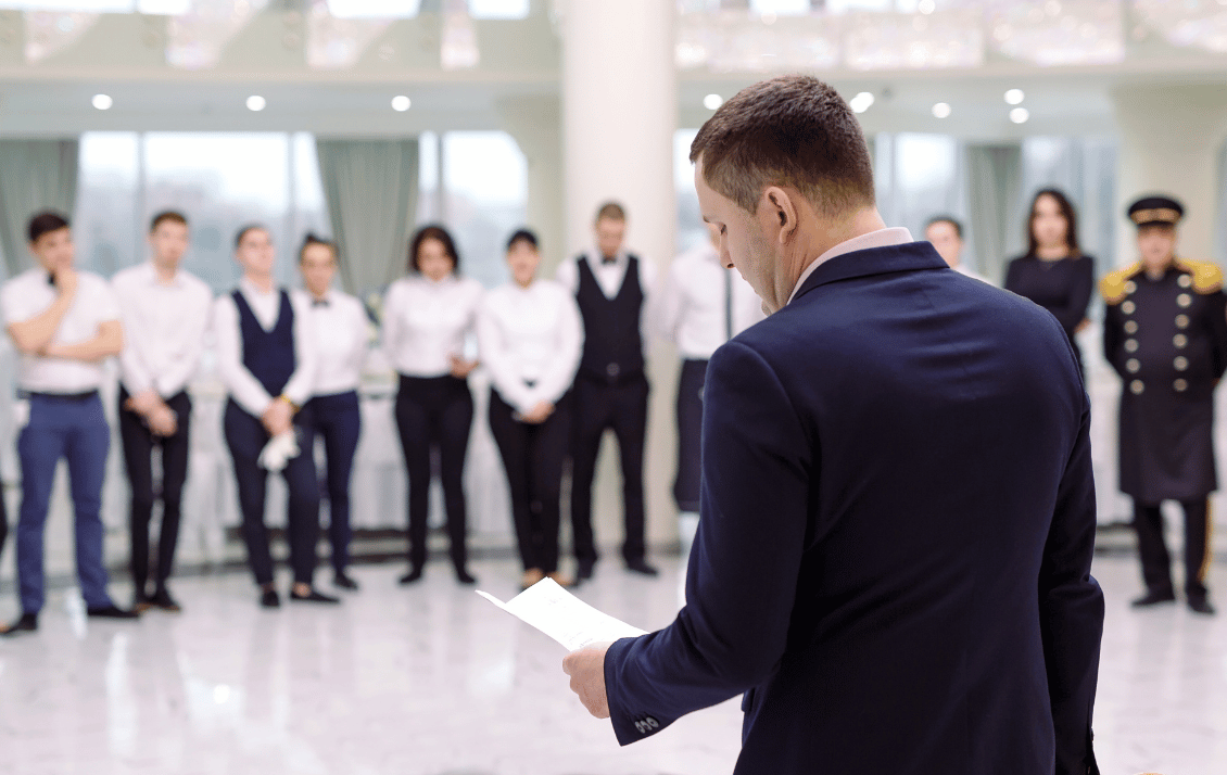 Hotel manager leading a team briefing before service across a multi-property hospitality operation