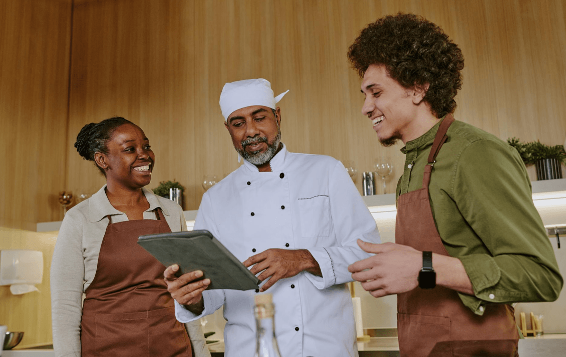 Hospitality manager reviewing compliance training with kitchen team using a tablet