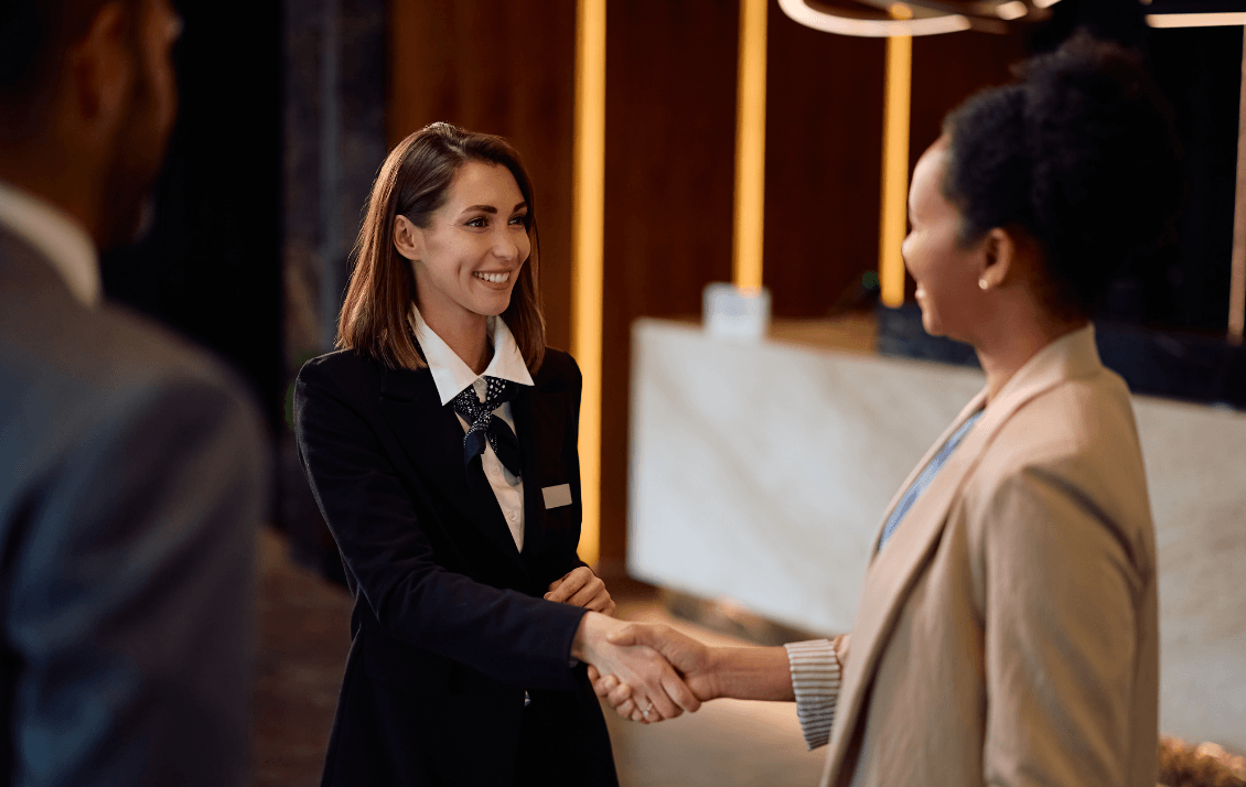 Hotel manager welcoming a guest at reception to deliver a consistent hospitality experience