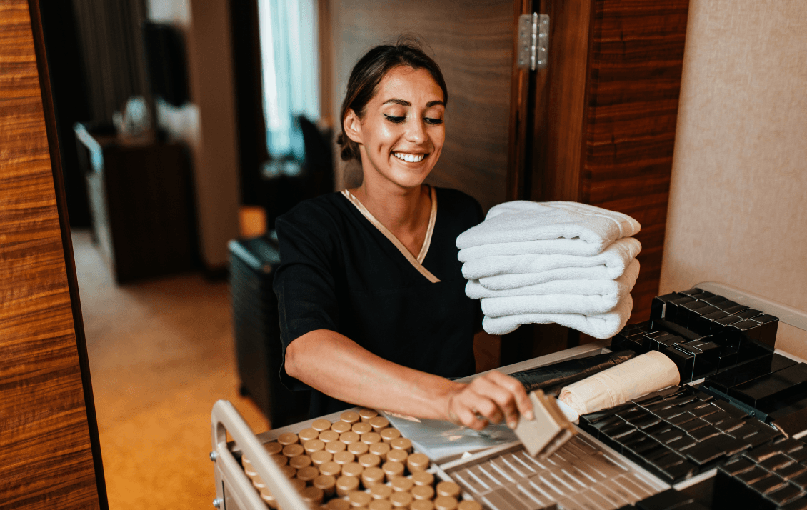 Housekeeping team member preparing fresh towels and room amenities on a housekeeping cart