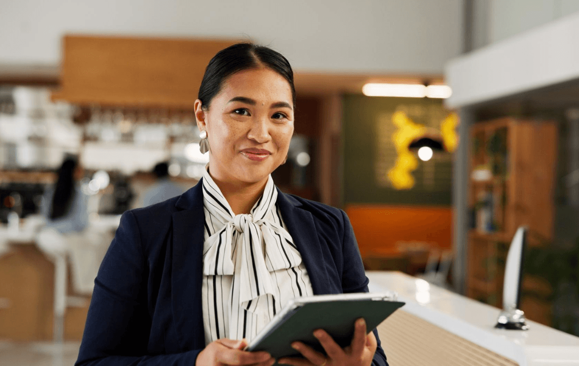 Hospitality owner or hotel manager holding a tablet while reviewing hotel performance in a modern lobby